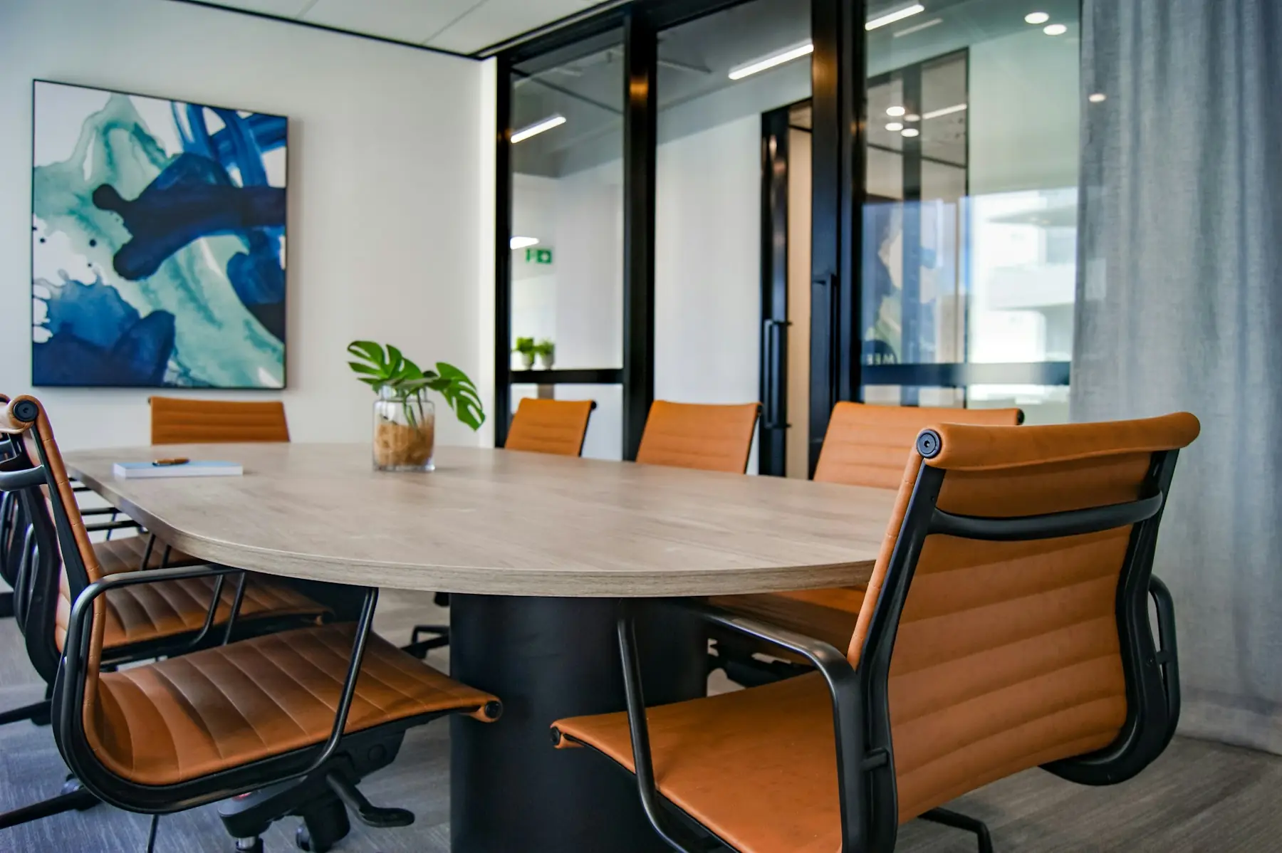 A bright meeting room with a round table and orange chairs